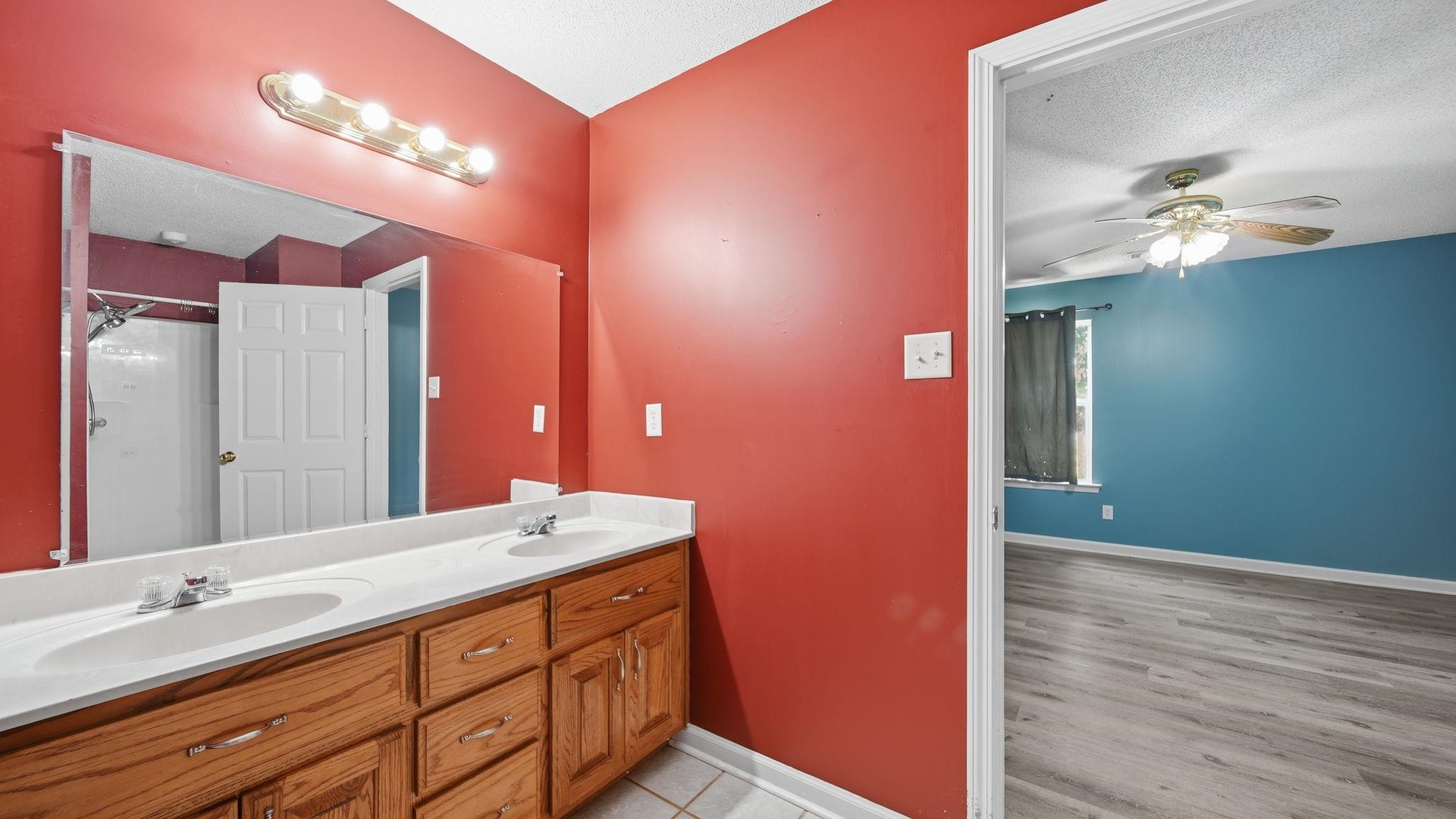 217 Rae Drive Munford, TN 38058 - Photo 21 of 40 Bathroom vanity featuring dual sinks, wood-finish cabinetry, and a full-width mirror