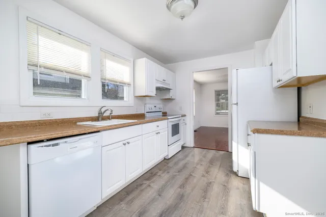 a large white kitchen with stainless steel appliances granite countertop a sink and cabinets