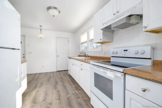 a kitchen with granite countertop white cabinets and white appliances