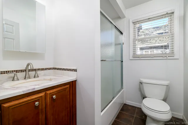 a bathroom with a granite countertop toilet a sink and a mirror