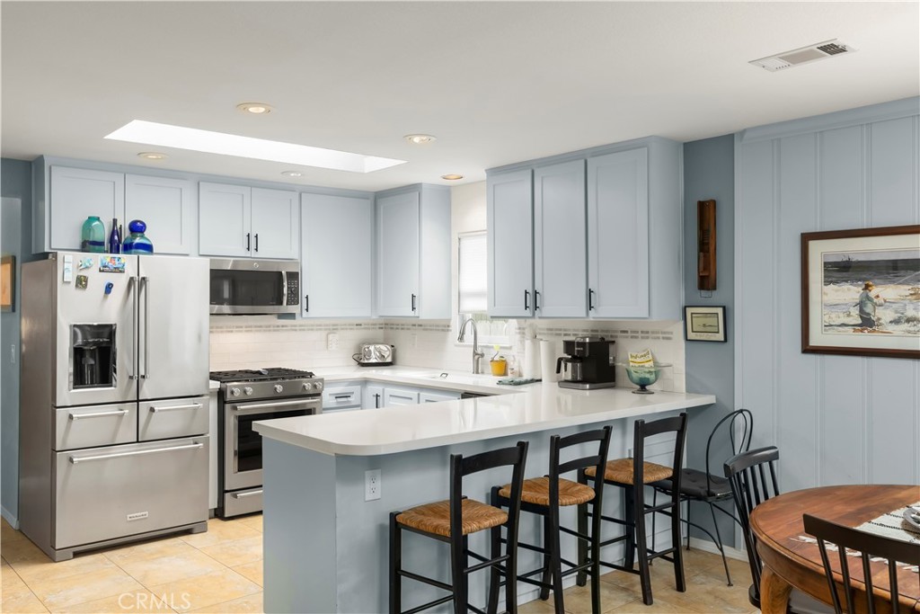 50 5th Street Cayucos, CA 93430 - Photo 21 of 47 a kitchen with stainless steel appliances a table chairs refrigerator and microwave