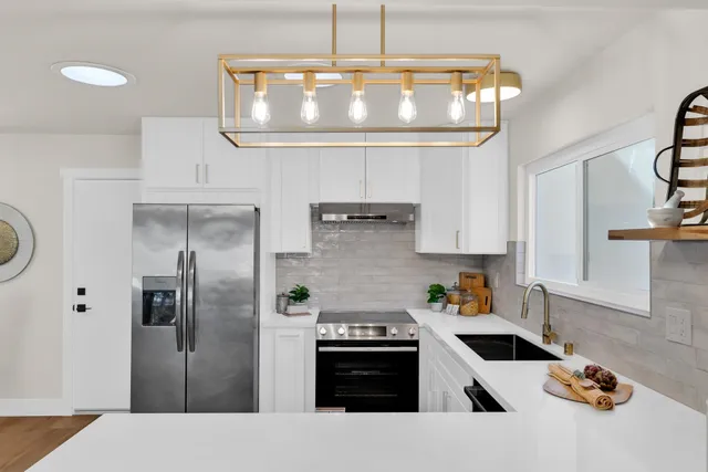 a kitchen with stainless steel appliances granite countertop a refrigerator a stove and a granite counter tops with white cabinets