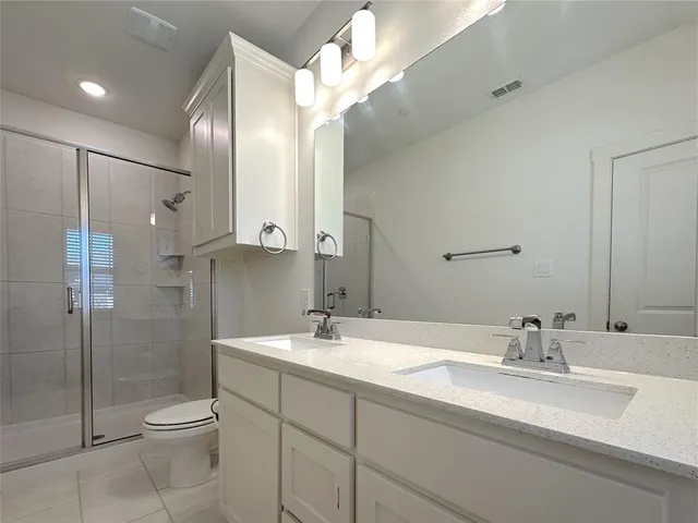 a bathroom with a double vanity sink toilet and shower