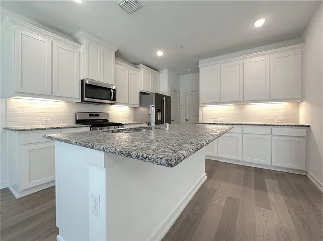a kitchen with kitchen island granite countertop a sink counter top space appliances and cabinets
