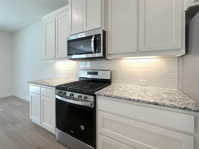 a kitchen with granite countertop white cabinets and appliances