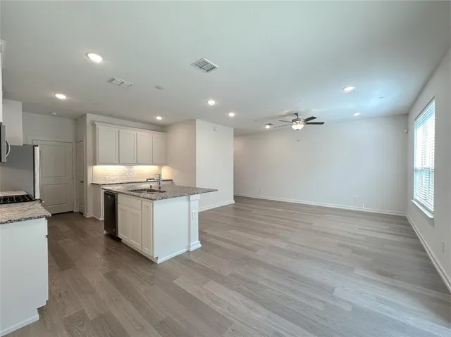 a large kitchen with a sink dishwasher a kitchen island a stove and a wooden floors