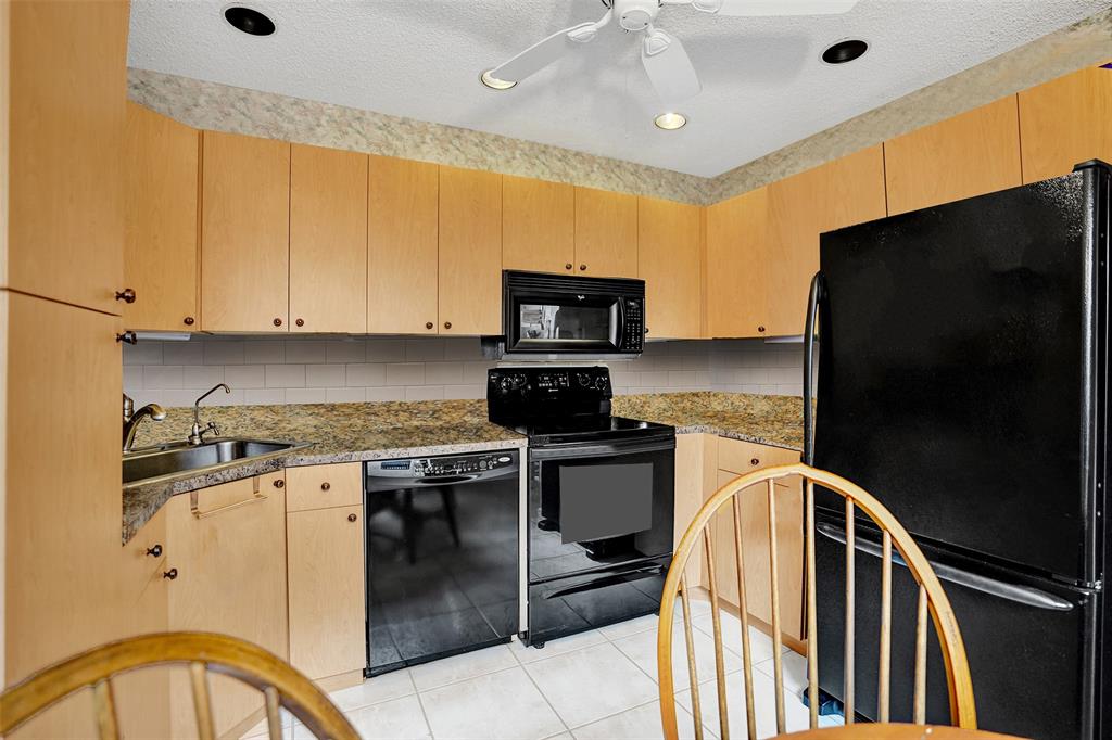 9132 Southwest 20th Street, Unit B Boca Raton, FL 33428 - Photo 16 of 81 a kitchen with granite countertop a stove top oven microwave and refrigerator