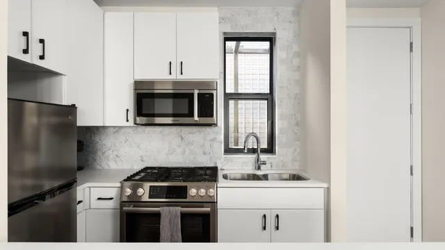 a kitchen with stainless steel appliances granite countertop a stove a sink and a microwave