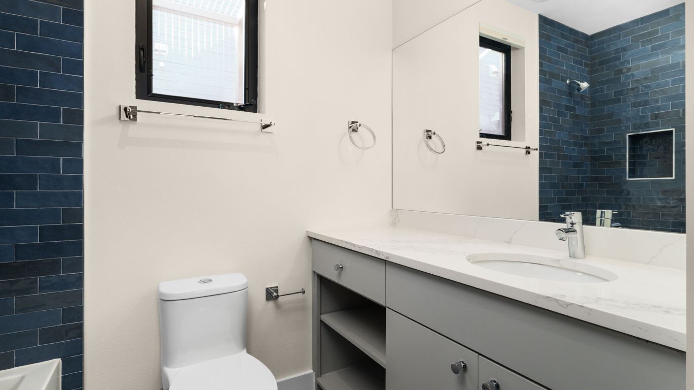 3813 Tilley Street Austin, TX 78723 - Photo 22 of 26 a bathroom with a granite countertop sink a toilet and a mirror