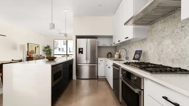 a kitchen with stainless steel appliances a refrigerator a stove and white cabinets