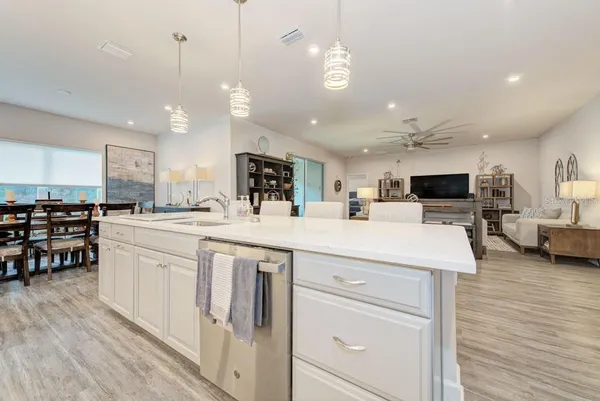 a large white kitchen with kitchen island a sink a center island and stainless steel appliances