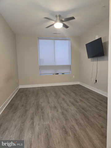 a view of an empty room with window and wooden floor