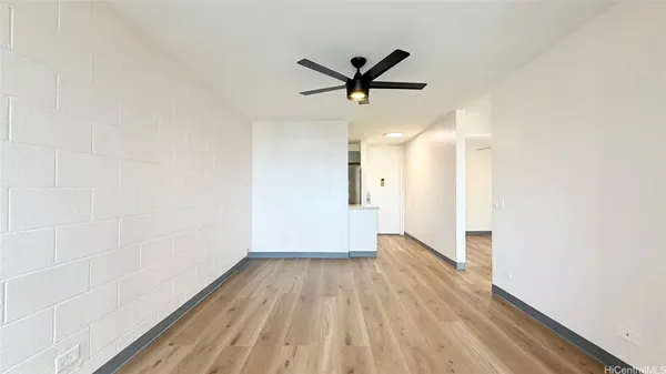 a view of empty room with wooden floor and fan