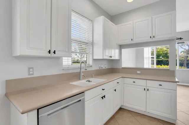 a kitchen with white cabinets and a window