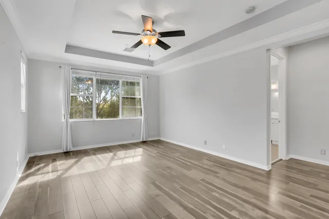 an empty room with wooden floor ceiling fan and window