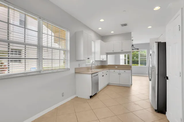 a large kitchen with granite countertop a large window and white stainless steel appliances