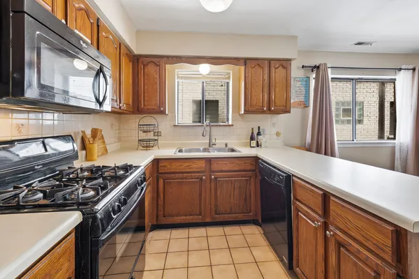 a kitchen with stainless steel appliances granite countertop a stove a sink dishwasher and a microwave oven with large cabinets
