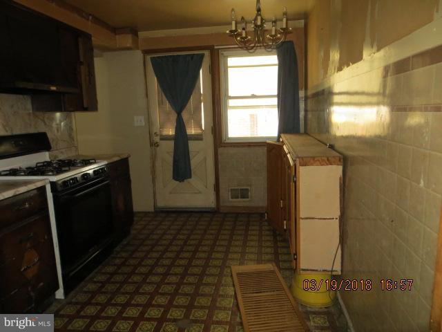 8149 Del Haven Road Baltimore, MD 21222 - Photo 6 of 18 a kitchen with a refrigerator a stove a microwave and cabinets