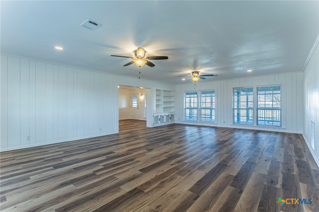 301 Thomas Street Rogers, TX 76569 - Photo 3 of 29 an empty room with wooden floor chandelier fan and windows