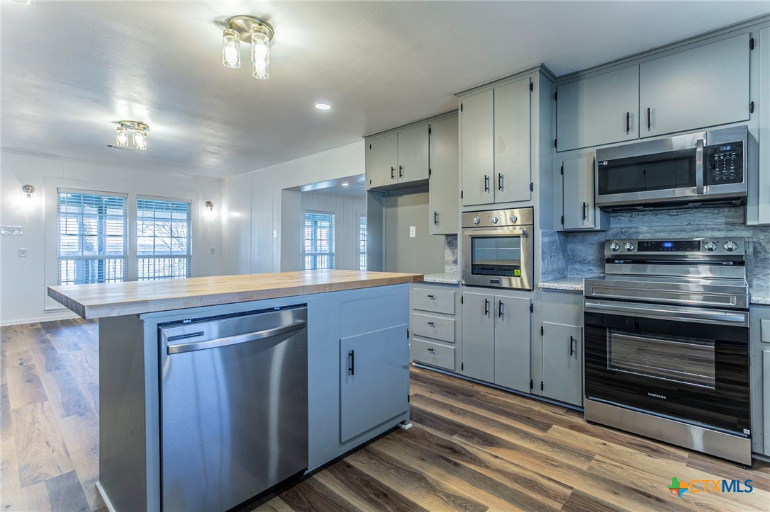 301 Thomas Street Rogers, TX 76569 - Photo 7 of 29 a kitchen with stainless steel appliances granite countertop a stove a sink and a microwave