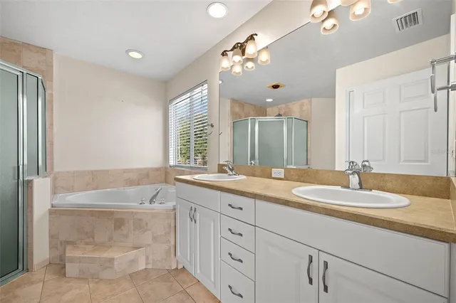 a bathroom with a granite countertop double vanity sink a bathtub a mirror and vanity