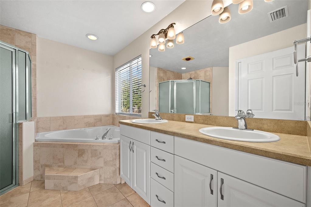 10215 Southwest 98th Avenue Gainesville, FL 32608 - Photo 22 of 43 a bathroom with a granite countertop double vanity sink a bathtub a mirror and vanity
