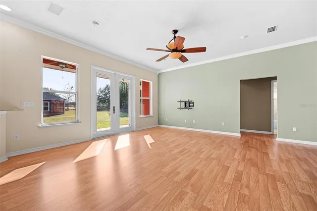 a view of an empty room with a window and wooden floor