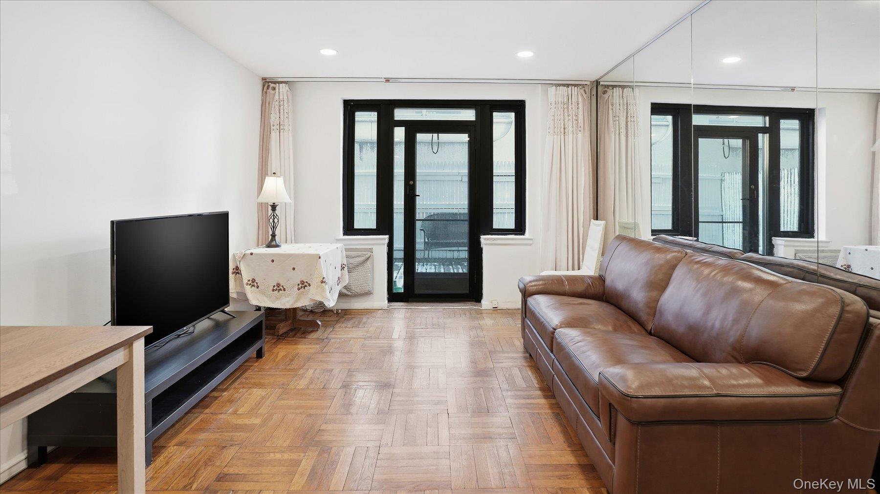 46 Grace Avenue, Unit 1L Great Neck, NY 11021 - Photo 7 of 16 a living room with furniture and a flat screen tv