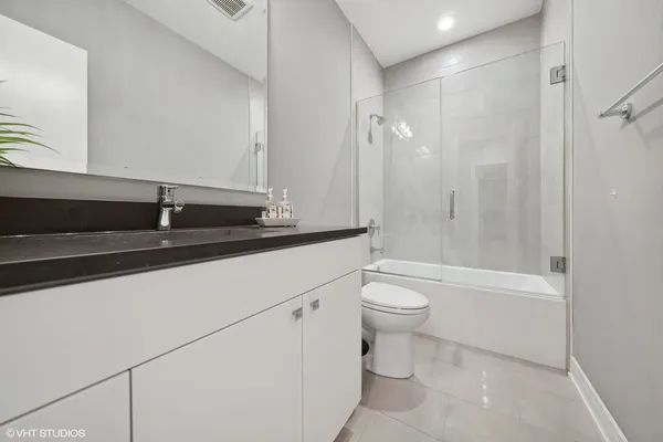 a bathroom with a granite countertop sink a toilet a mirror and shower