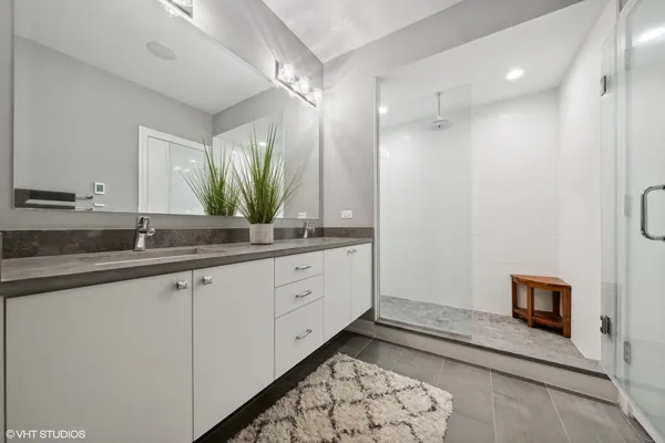 a spacious bathroom with a double vanity sink a mirror and a shower