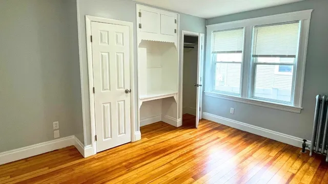 a view of an empty room with window and wooden floor