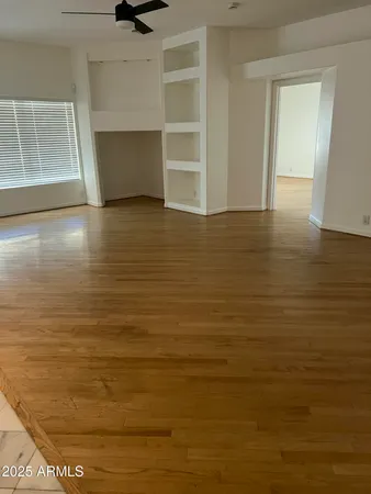 a view of an empty room with wooden floor and a window