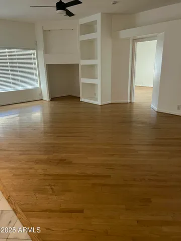 a view of an empty room with wooden floor and a window