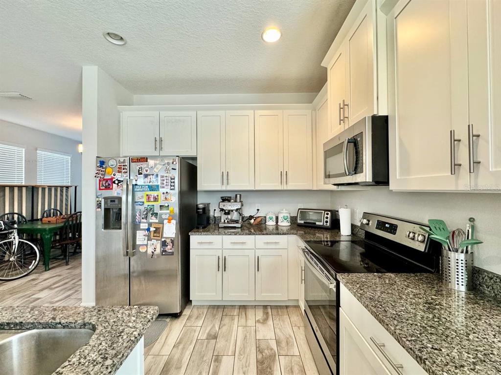 2951 West Cherry Street Tampa, FL 33607 - Photo 12 of 25 a kitchen with stainless steel appliances granite countertop a stove top oven a sink a dining table and chairs with wooden floor