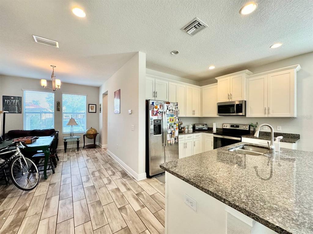 2951 West Cherry Street Tampa, FL 33607 - Photo 8 of 25 a kitchen with stainless steel appliances granite countertop a refrigerator a stove top oven a sink a dining table and chairs with wooden floor