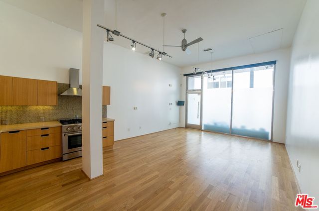 an empty room with wooden floor cabinet and windows