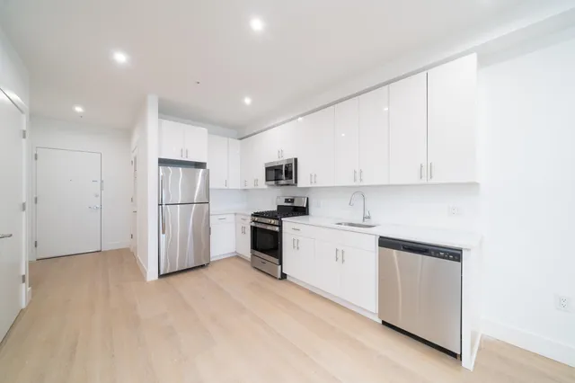 a kitchen with white cabinets and refrigerator