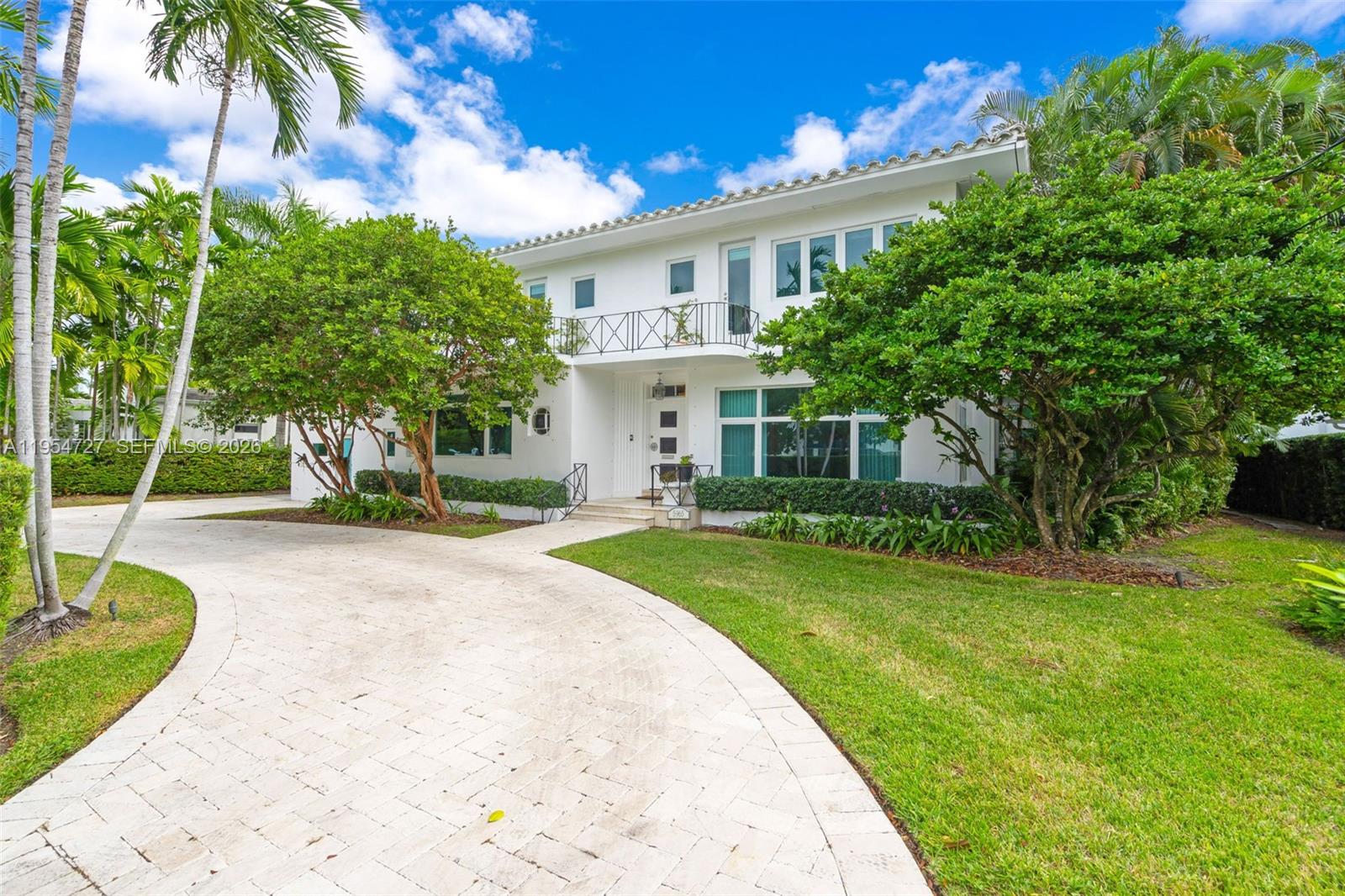 5965 Alton Road Miami Beach, FL 33140 - Photo 10 of 29 a view of a white house with a big yard plants and large trees