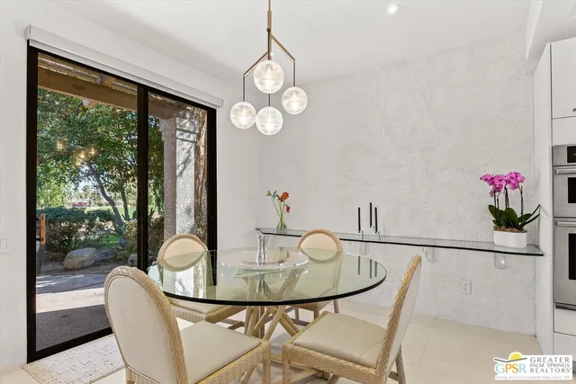 a view of a dining room with furniture a potted plant and a floor to ceiling window