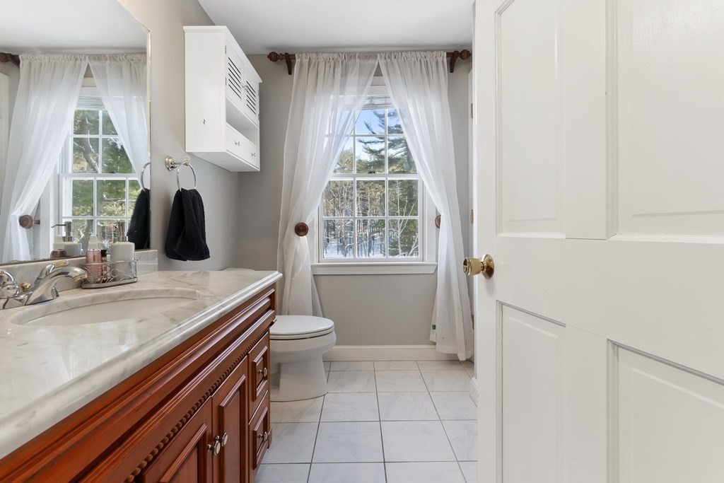 64 Jenkins Road Andover, MA 01810 - Photo 20 of 31 a bathroom with a granite countertop toilet a sink and a window