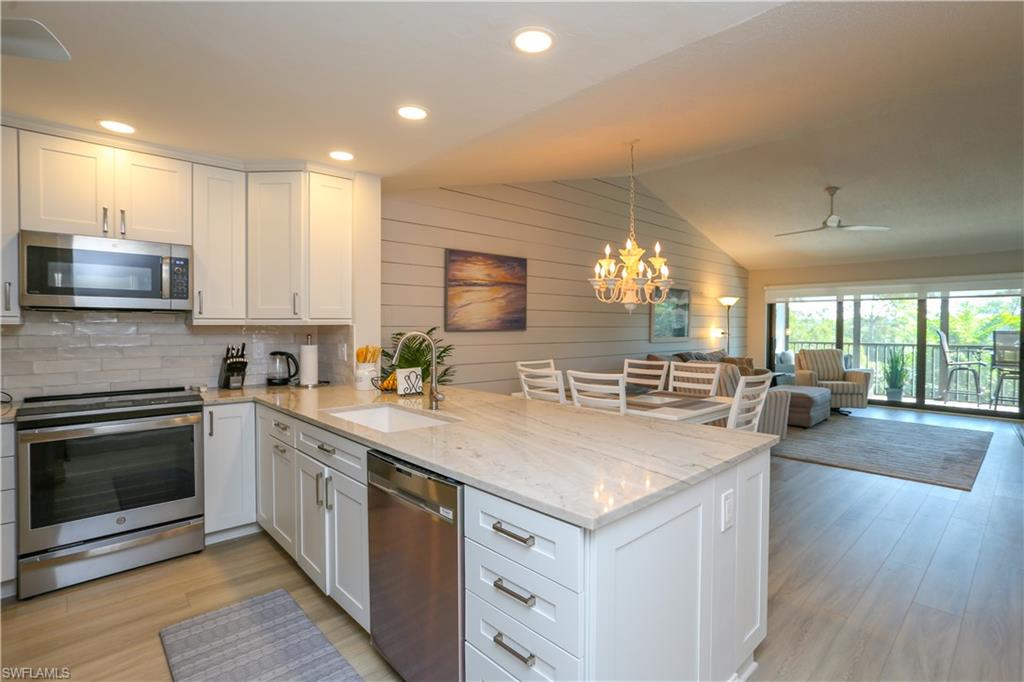 a kitchen with stainless steel appliances a sink dishwasher stove and oven with wooden floor