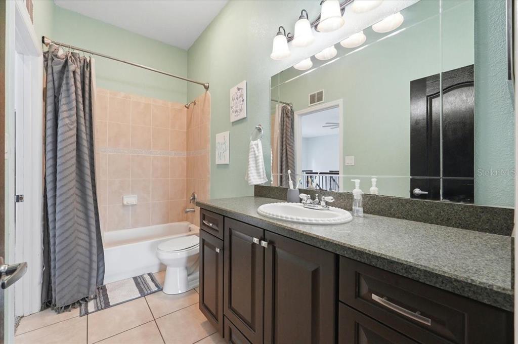 3943 West Campbell Road Lakeland, FL 33810 - Photo 79 of 95 a bathroom with a granite countertop sink a toilet a mirror a vanity and shower