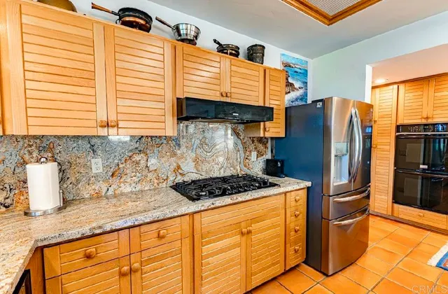 a kitchen with stainless steel appliances granite countertop a stove a sink and a refrigerator
