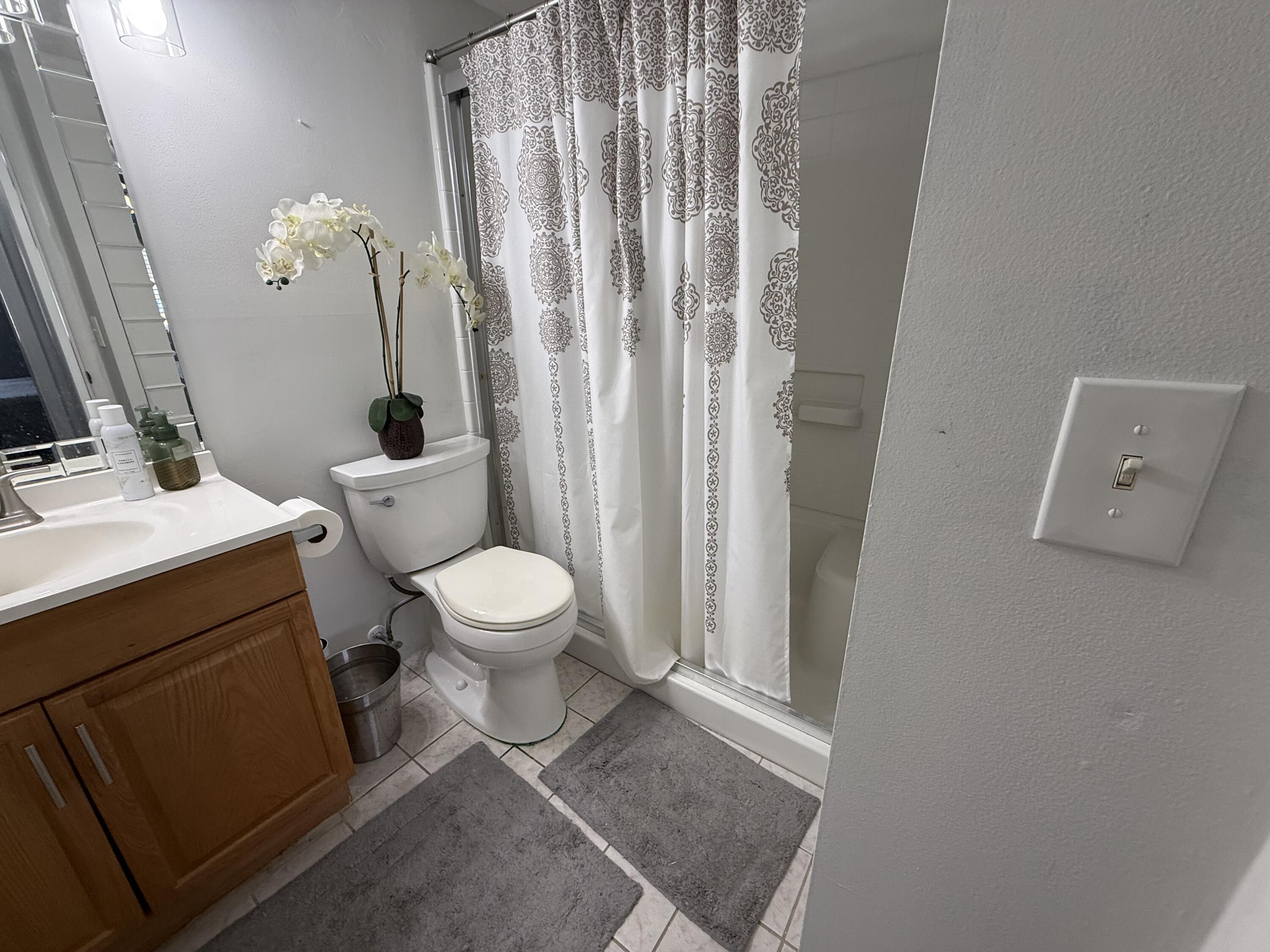 301 Pine Ridge Circle, Unit B1 Greenacres, FL 33463 - Photo 11 of 12 a bathroom with a toilet a sink and a mirror