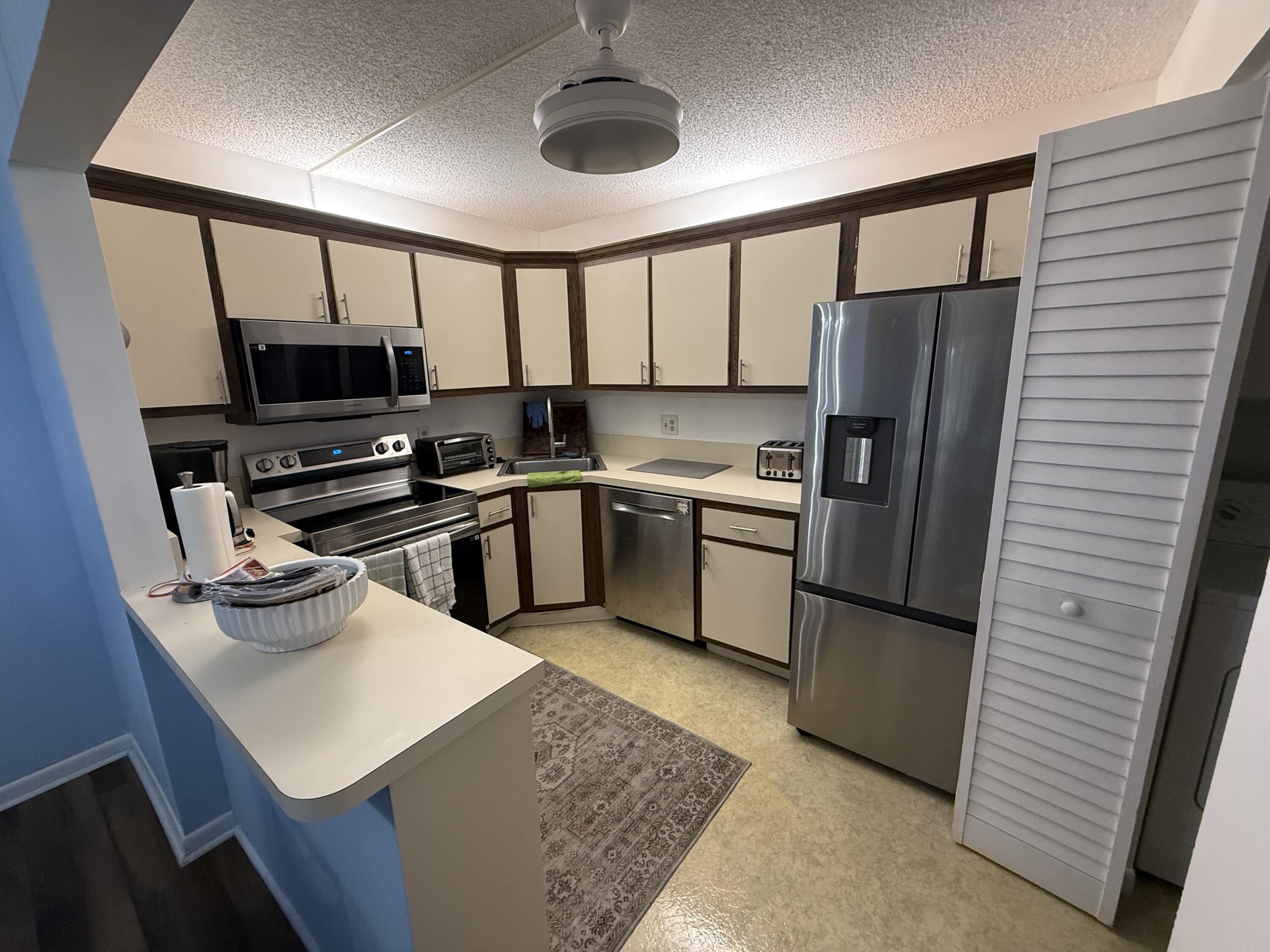 301 Pine Ridge Circle, Unit B1 Greenacres, FL 33463 - Photo 6 of 12 a kitchen with a sink a refrigerator and a stove