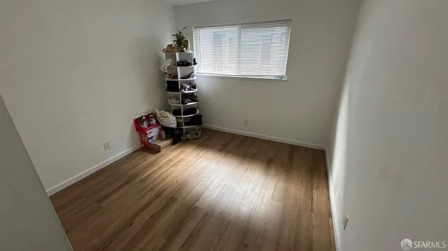 an empty room with wooden floor closet and windows