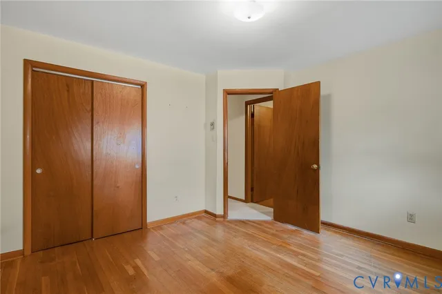 an empty room with wooden floor and closet area