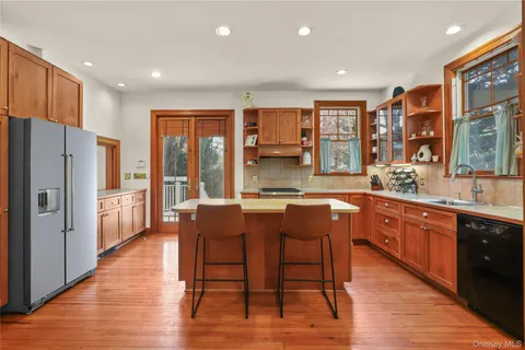 a kitchen with stainless steel appliances granite countertop a refrigerator a sink dishwasher a dining table and chairs with wooden floor