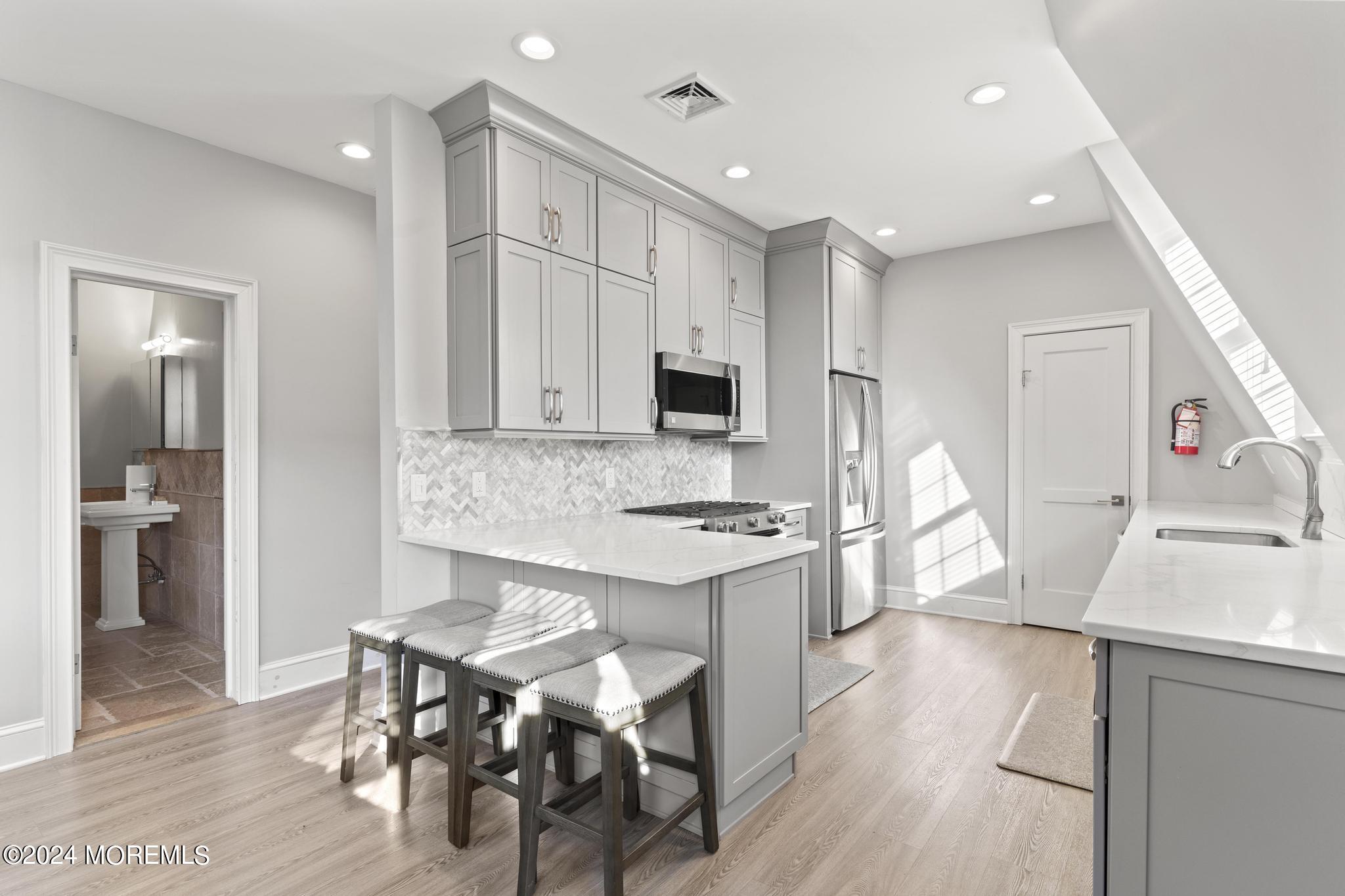 892 Elberon Avenue Long Branch, NJ 07740 - Photo 16 of 50 a kitchen with stainless steel appliances granite countertop a stove top oven a sink dishwasher and a refrigerator with wooden floor