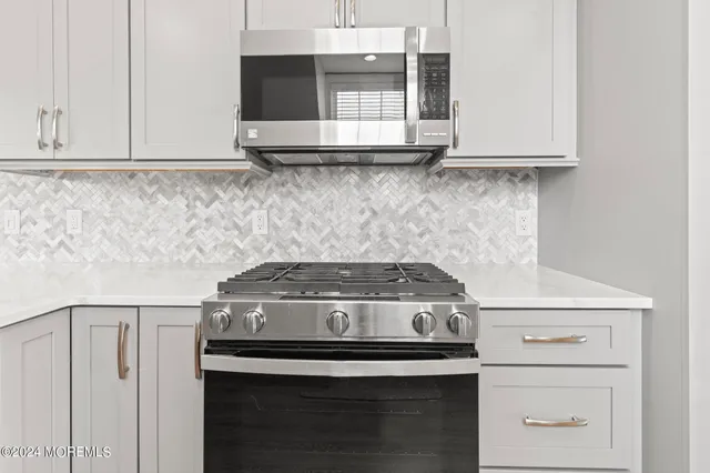 a kitchen with stainless steel appliances granite countertop a stove top oven a sink dishwasher and a refrigerator with wooden floor